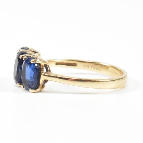 382 - A hallmarked 9ct gold and synthetic sapphire three stone ring. The ring having three four claw set o... 