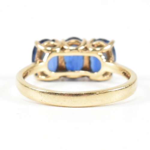 382 - A hallmarked 9ct gold and synthetic sapphire three stone ring. The ring having three four claw set o... 