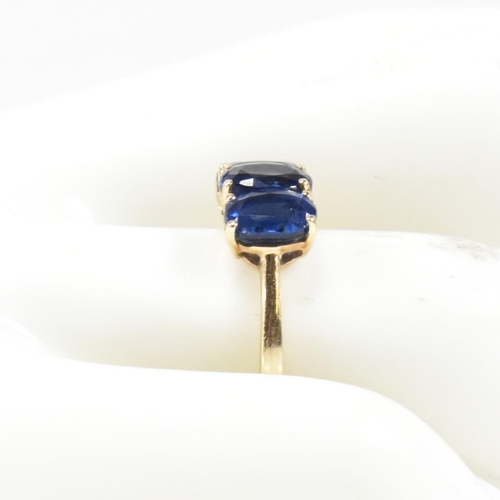 382 - A hallmarked 9ct gold and synthetic sapphire three stone ring. The ring having three four claw set o... 