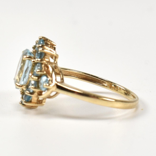 398 - A hallmarked 9ct gold and topaz cluster ring. The ring having a central four claw set oval cut topaz... 