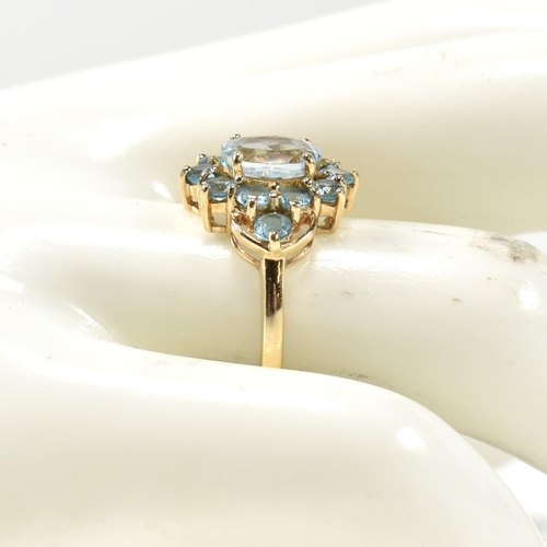 398 - A hallmarked 9ct gold and topaz cluster ring. The ring having a central four claw set oval cut topaz... 