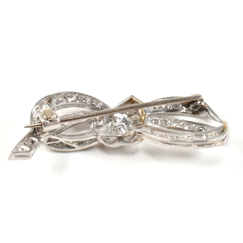 40 - An Art Deco platinum gold and diamond ribbon bow brooch pin. The brooch set with single baguette and... 