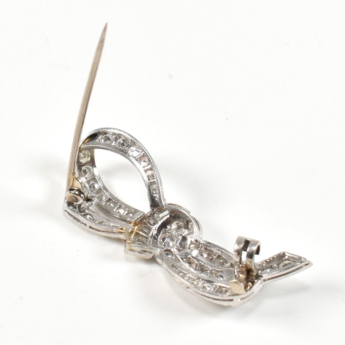 40 - An Art Deco platinum gold and diamond ribbon bow brooch pin. The brooch set with single baguette and... 