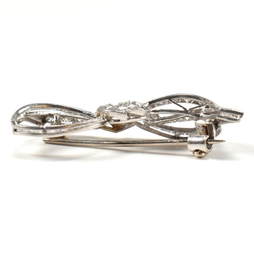 40 - An Art Deco platinum gold and diamond ribbon bow brooch pin. The brooch set with single baguette and... 