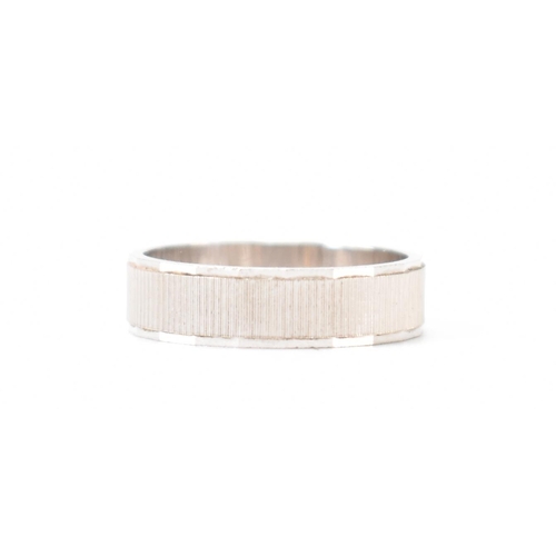 403 - An Italian 18ct white gold band ring. The ring having textured sides with faceted borders. Italian a... 