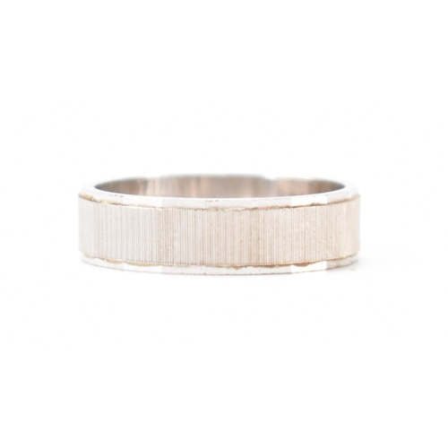 403 - An Italian 18ct white gold band ring. The ring having textured sides with faceted borders. Italian a... 