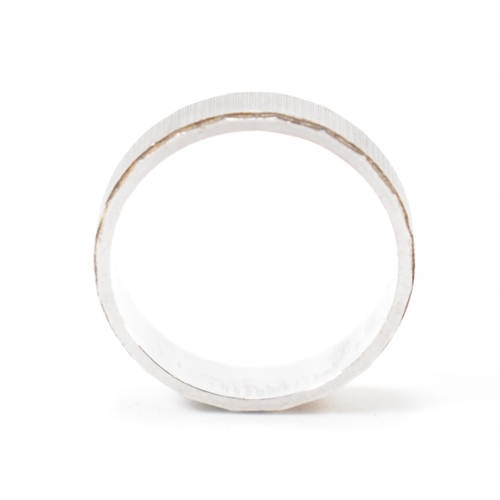 403 - An Italian 18ct white gold band ring. The ring having textured sides with faceted borders. Italian a... 