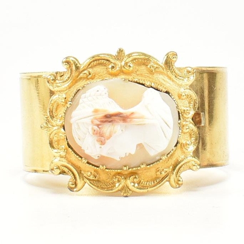 415 - A 19th century shell cameo double hinged gilt bangle. The Georgian bangle having a central carved ca... 