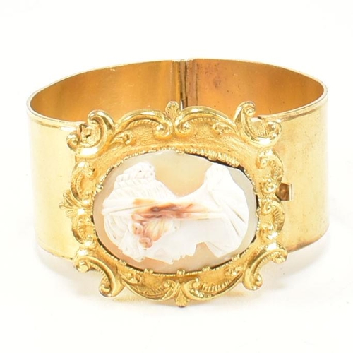 415 - A 19th century shell cameo double hinged gilt bangle. The Georgian bangle having a central carved ca... 