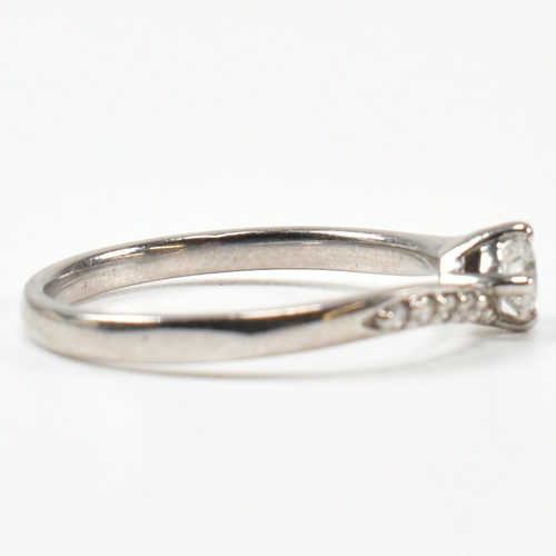 425 - A hallmarked 18ct white gold and diamond crossover ring. The ring set with a central button claw set... 