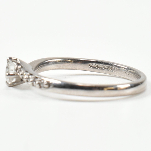 425 - A hallmarked 18ct white gold and diamond crossover ring. The ring set with a central button claw set... 