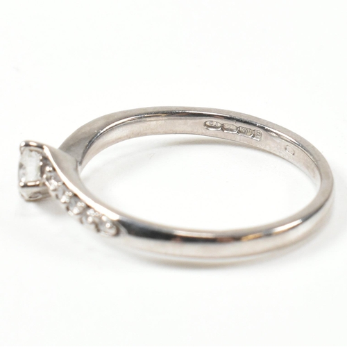 425 - A hallmarked 18ct white gold and diamond crossover ring. The ring set with a central button claw set... 