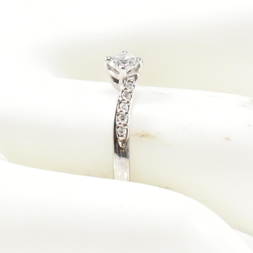 425 - A hallmarked 18ct white gold and diamond crossover ring. The ring set with a central button claw set... 