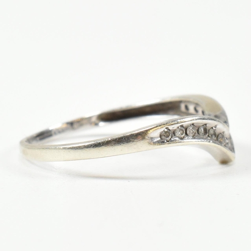 426 - A hallmarked 9ct white gold and diamond wish bone ring. The wishbone ring set with a row of graduati... 