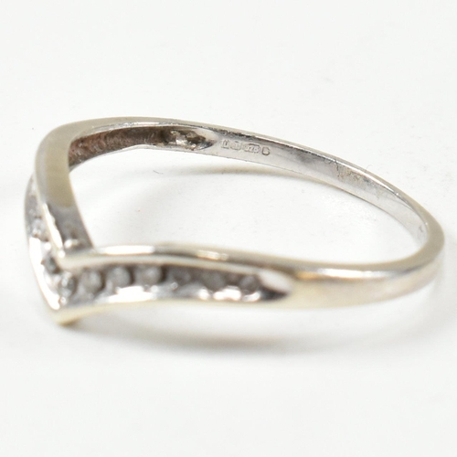 426 - A hallmarked 9ct white gold and diamond wish bone ring. The wishbone ring set with a row of graduati... 