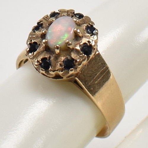 432 - A hallmarked 9ct gold, sapphire and opal cluster ring. The ring set with a central opal cabochon and... 