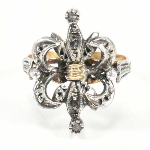 436 - A Fleur de lis diamond cluster ring. The ring having a diamond set a fleur de lis motif to ribbed ba... 