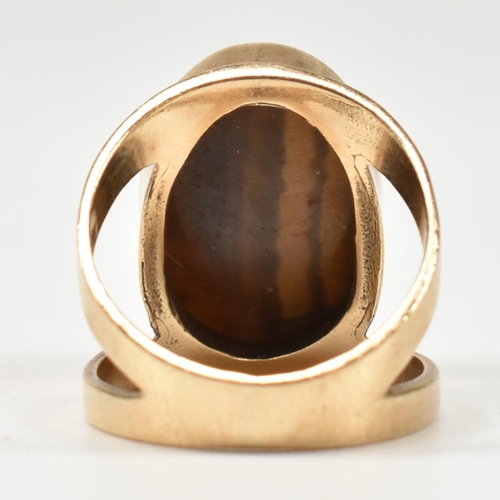 69 - A hallmarked 9ct gold and tiger's eye ring. The ring set with a central bezel set oval tiger's eye c... 