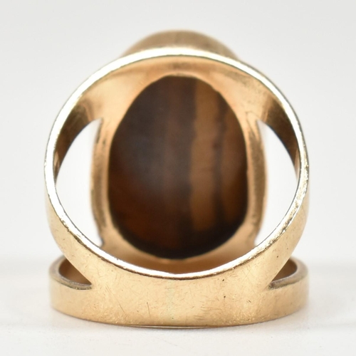 69 - A hallmarked 9ct gold and tiger's eye ring. The ring set with a central bezel set oval tiger's eye c... 