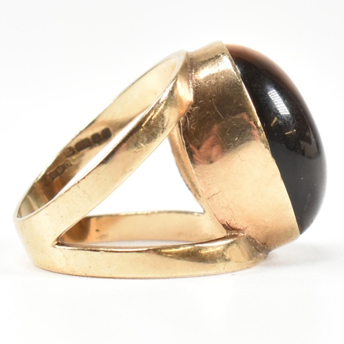 69 - A hallmarked 9ct gold and tiger's eye ring. The ring set with a central bezel set oval tiger's eye c... 