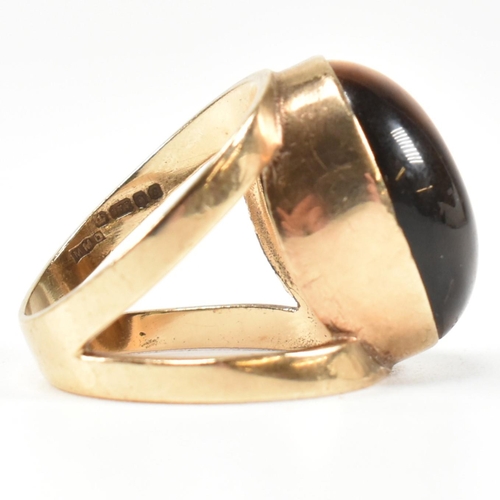 69 - A hallmarked 9ct gold and tiger's eye ring. The ring set with a central bezel set oval tiger's eye c... 