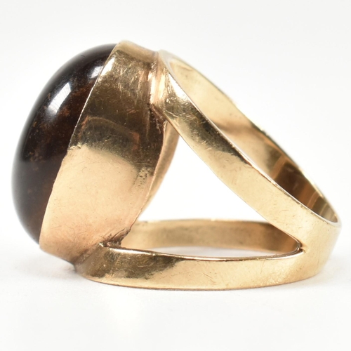 69 - A hallmarked 9ct gold and tiger's eye ring. The ring set with a central bezel set oval tiger's eye c... 