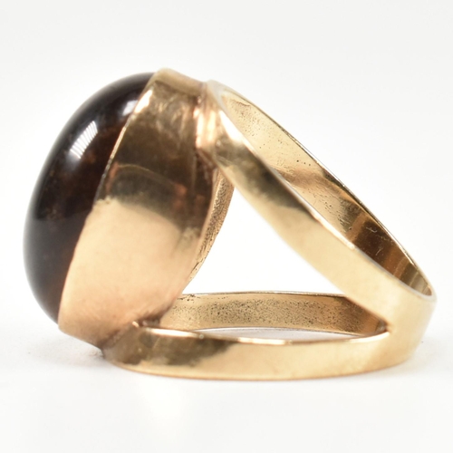 69 - A hallmarked 9ct gold and tiger's eye ring. The ring set with a central bezel set oval tiger's eye c... 