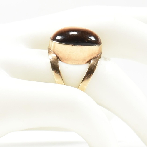 69 - A hallmarked 9ct gold and tiger's eye ring. The ring set with a central bezel set oval tiger's eye c... 