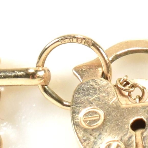 92 - A hallmarked 9ct gold gate link bracelet with heart padlock clasp. The 9ct gold gate link having a h... 