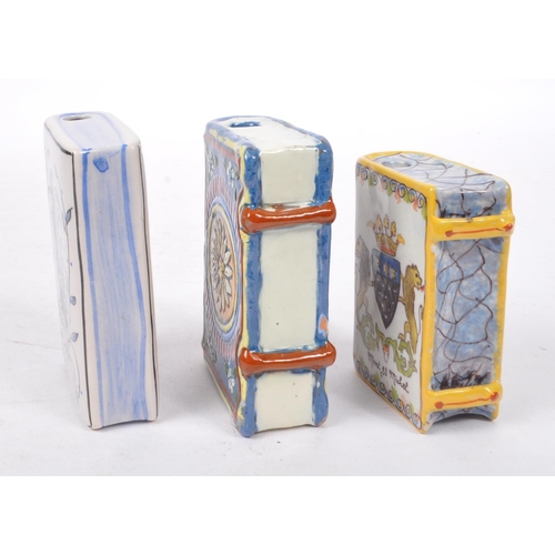 125 - A collection of three ceramic hand painted bottles in the form of books, one having ' Mont St Michel... 