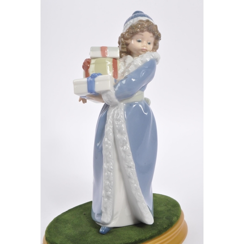 182 - Nao by Lladro - A 20th Century china porcelain Nao by Lladro ' Christmas Time ' figurine of girl in ... 