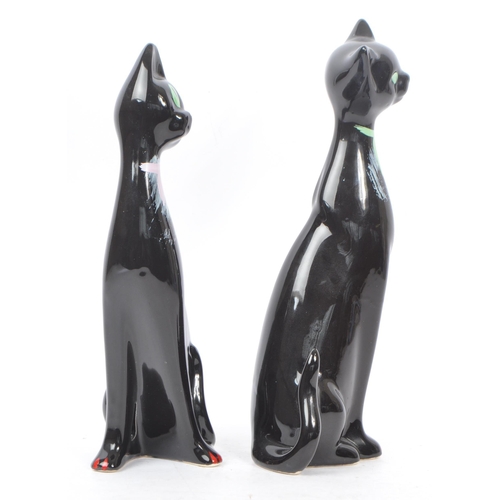 195 - A pair of contemporary ceramic / pottery cat figures / statues. Both in a seated position with hand ... 