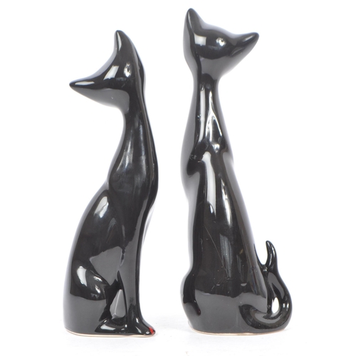 195 - A pair of contemporary ceramic / pottery cat figures / statues. Both in a seated position with hand ... 