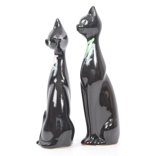 195 - A pair of contemporary ceramic / pottery cat figures / statues. Both in a seated position with hand ... 