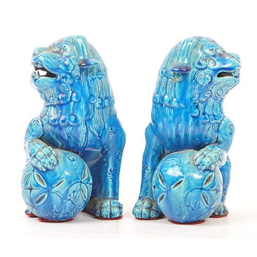 198 - A pair of vintage 20th century ceramic pottery temple guardian Fu dogs. In blue colourway, with paw ... 