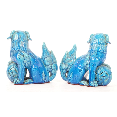 198 - A pair of vintage 20th century ceramic pottery temple guardian Fu dogs. In blue colourway, with paw ... 