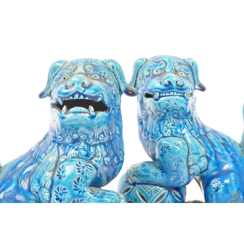 198 - A pair of vintage 20th century ceramic pottery temple guardian Fu dogs. In blue colourway, with paw ... 