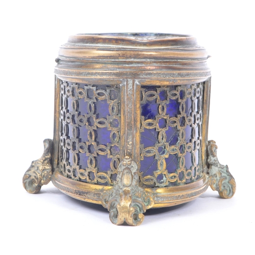 235 - An early 20th Century brass and blue glass trinket box of ovoid shape with hinged lid upon four deco... 