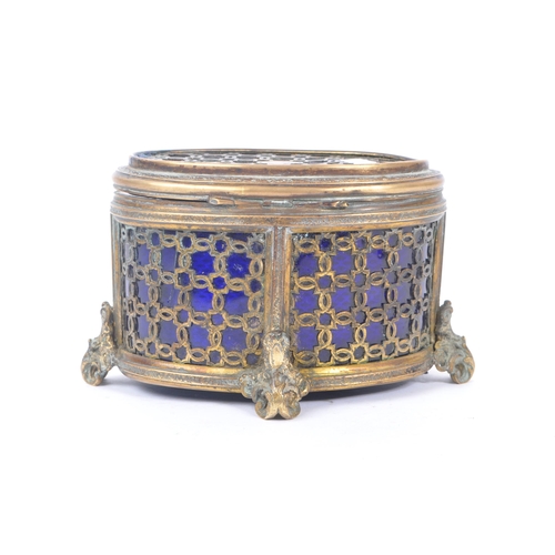 235 - An early 20th Century brass and blue glass trinket box of ovoid shape with hinged lid upon four deco... 