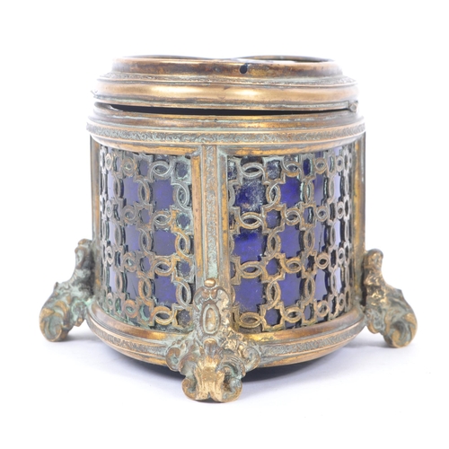 235 - An early 20th Century brass and blue glass trinket box of ovoid shape with hinged lid upon four deco... 