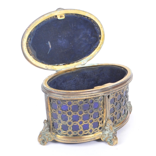 235 - An early 20th Century brass and blue glass trinket box of ovoid shape with hinged lid upon four deco... 