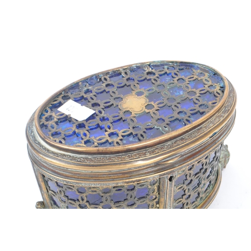 235 - An early 20th Century brass and blue glass trinket box of ovoid shape with hinged lid upon four deco... 