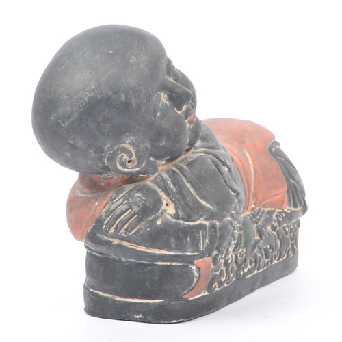 33 - An early 20th Century Chinese ceramic / clay pillow in the form of a lounging Buddha like / baby fig... 