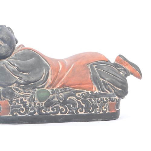 33 - An early 20th Century Chinese ceramic / clay pillow in the form of a lounging Buddha like / baby fig... 