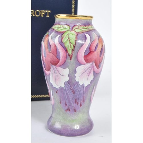 63 - Moorcroft Pottery - A contemporary small proportion vase. Fuchsia flowers with gilt rim. Signed and ... 