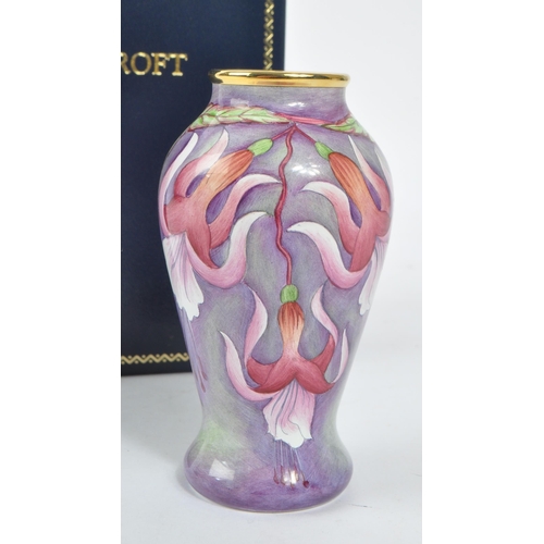 63 - Moorcroft Pottery - A contemporary small proportion vase. Fuchsia flowers with gilt rim. Signed and ... 