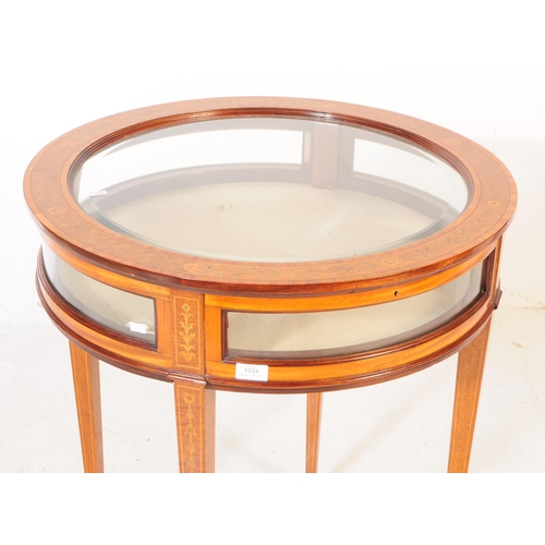 1034 - A 1920s inlaid bijouterie glass display table. Of circular form with glass panel to top, curved glas... 