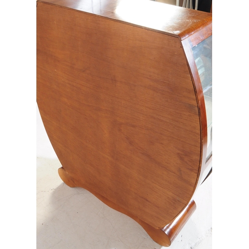 589 - A vintage mid 20th century circa. 1950s walnut display cabinet. The cabinet of rounded form with gla... 