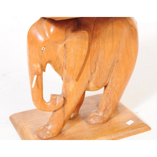 613 - A 20th century carved oak wood elephant stool. The stool in the form of a carved elephant, stood on ... 