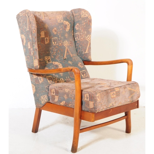 715 - A retro mid 20th century elm wood wingback armchair / lounge chair. The chair featuring bentwood arm... 